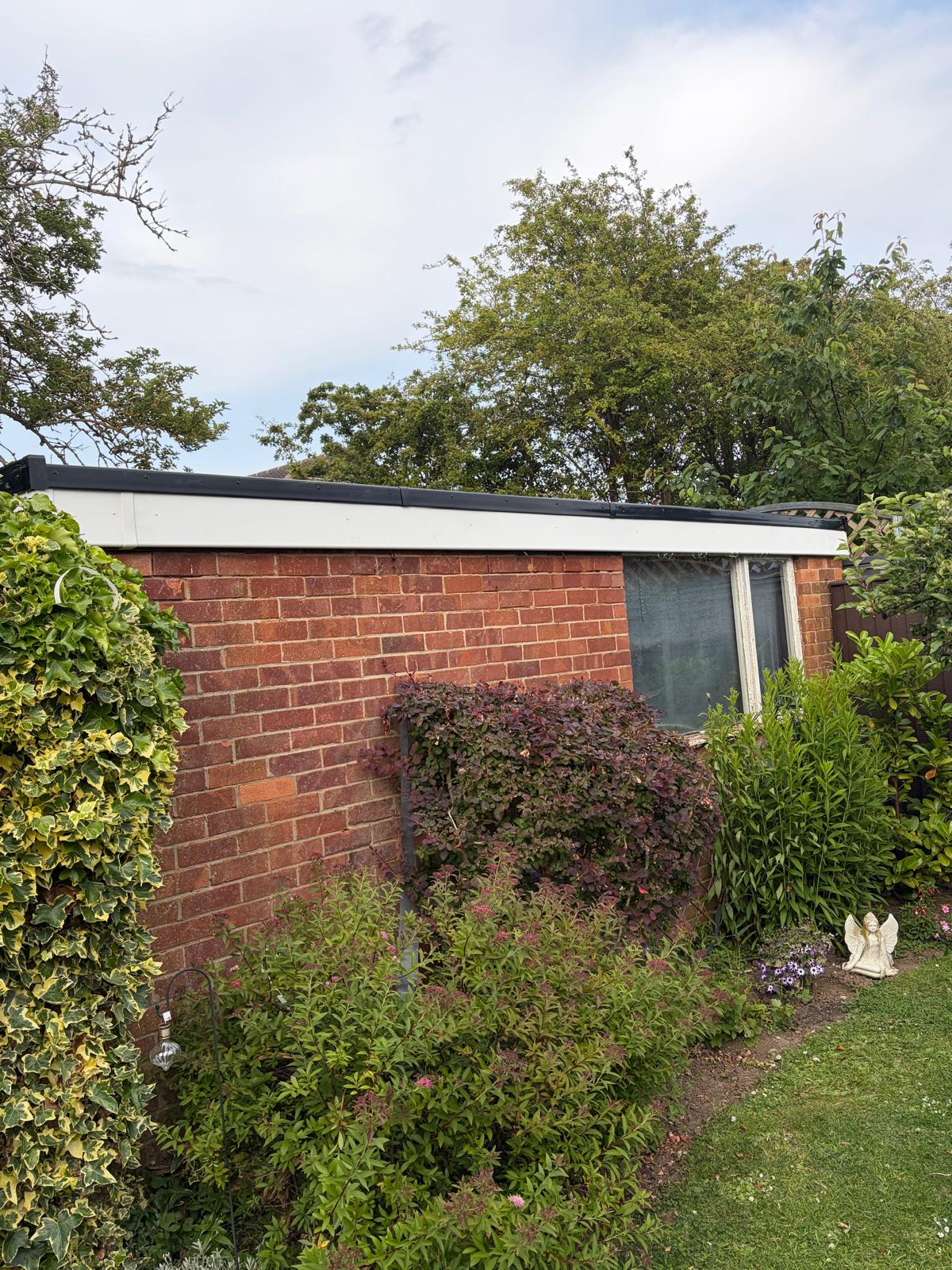 New EPDM flat roof with black trim on a brick garage